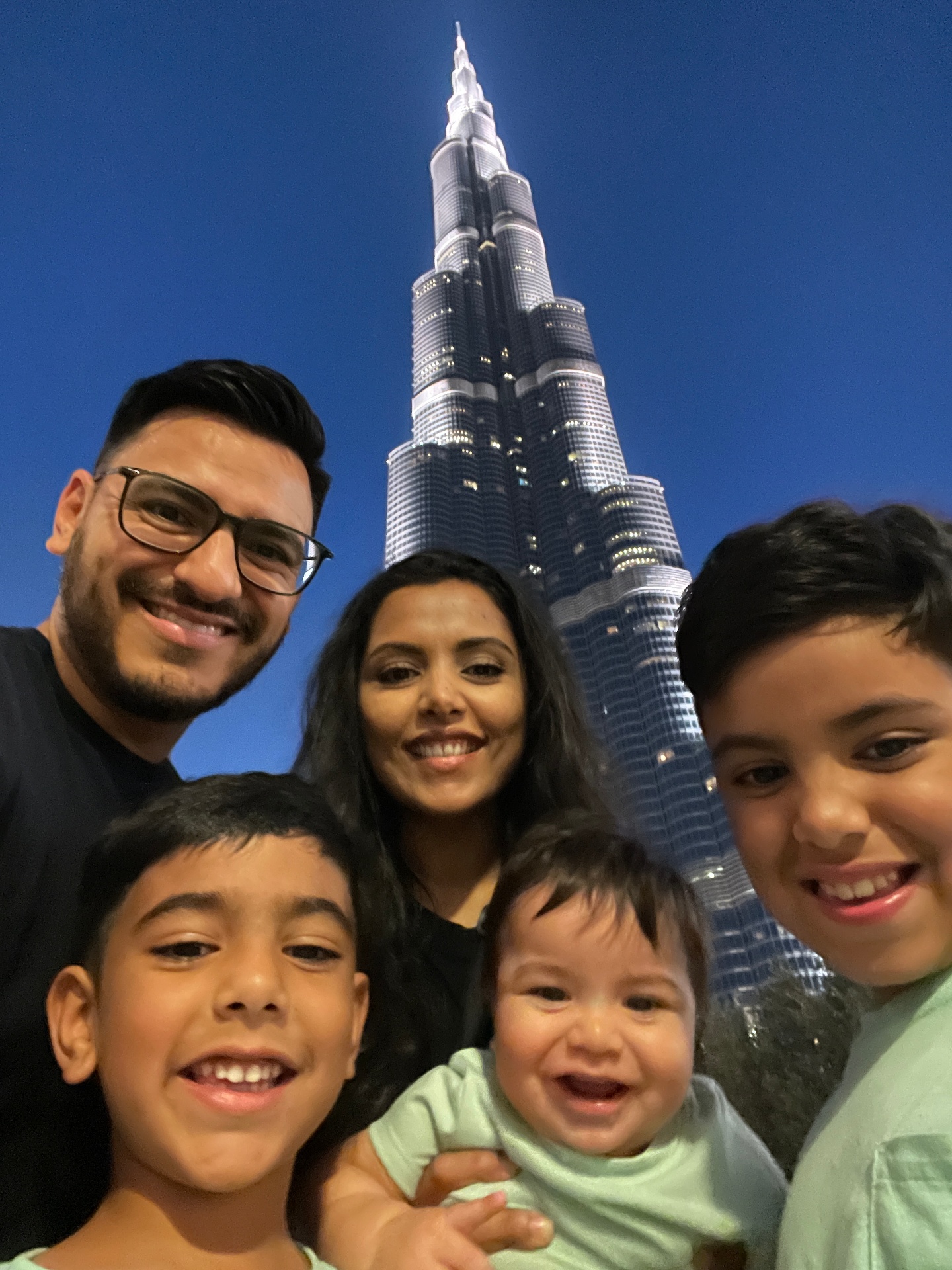 Eddie and his family in front of the Burj Khalifa in Dubai at dusk.